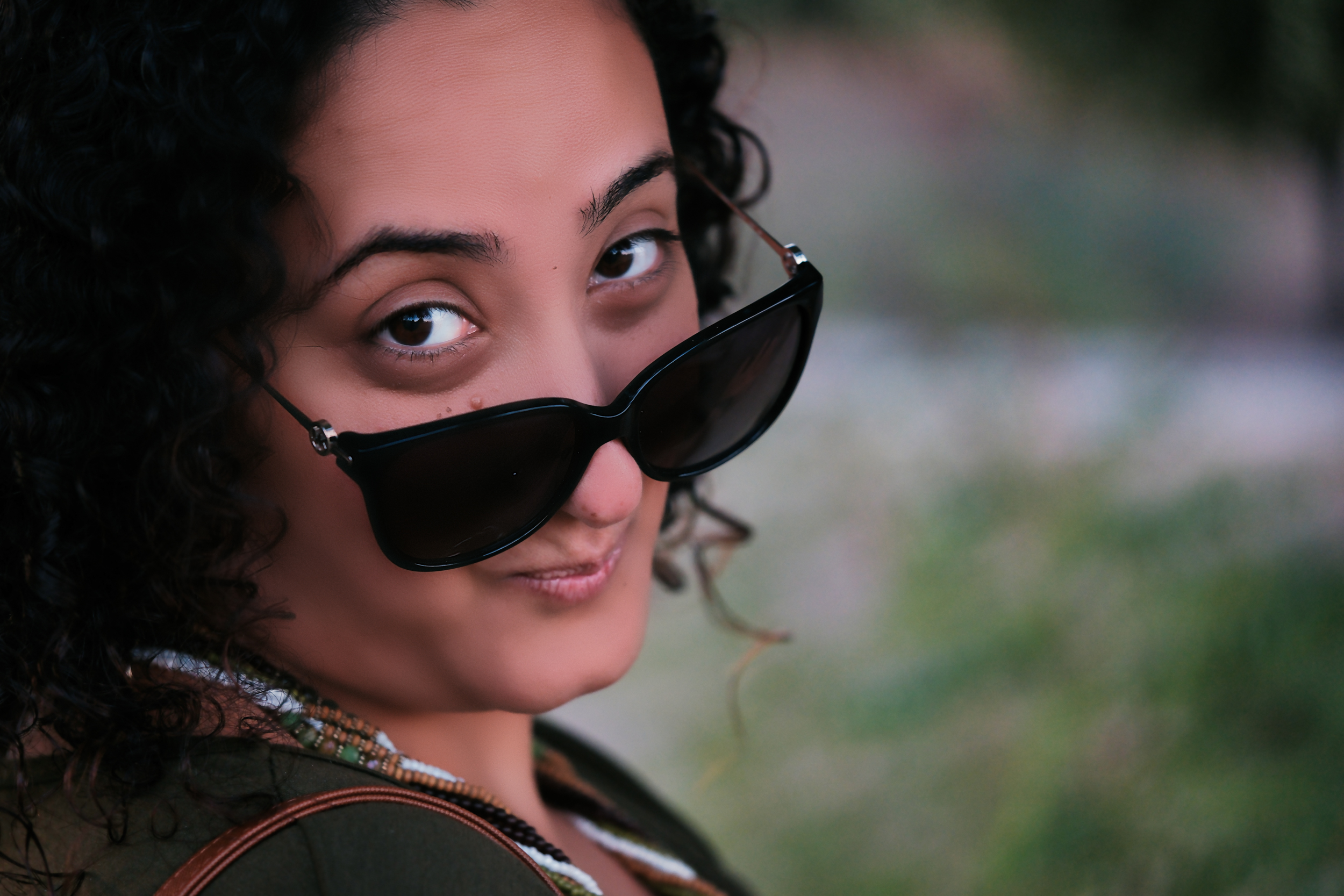 A mysterious and playful Bunkin' peering over her sunglasses with a knowing and enchanting smile.